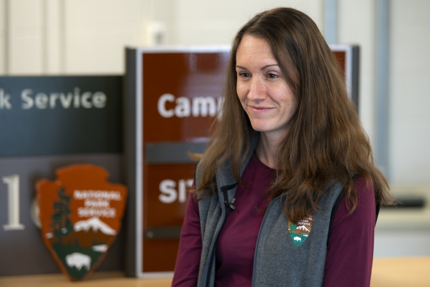 Visual Information Specialist Laura Thomas poses for a photo in front of NPS signs